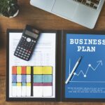 A business plan for a small company with a laptop, calculator and a cup of coffee.