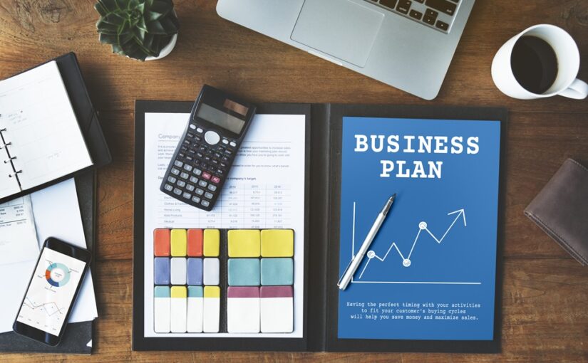 A business plan for a small company with a laptop, calculator and a cup of coffee.