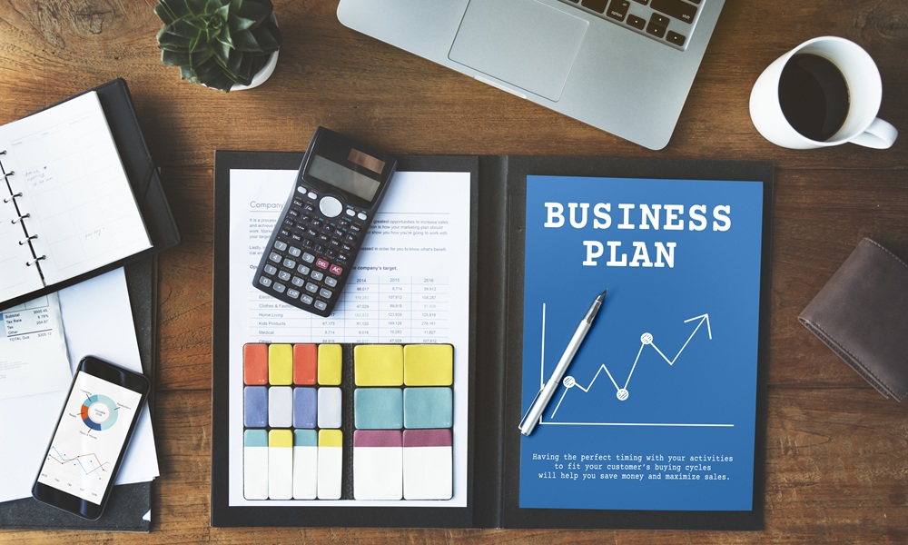 A business plan for a small company with a laptop, calculator and a cup of coffee.
