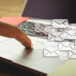 A finger on a laptop mouse board with images of envelopes overlaid.