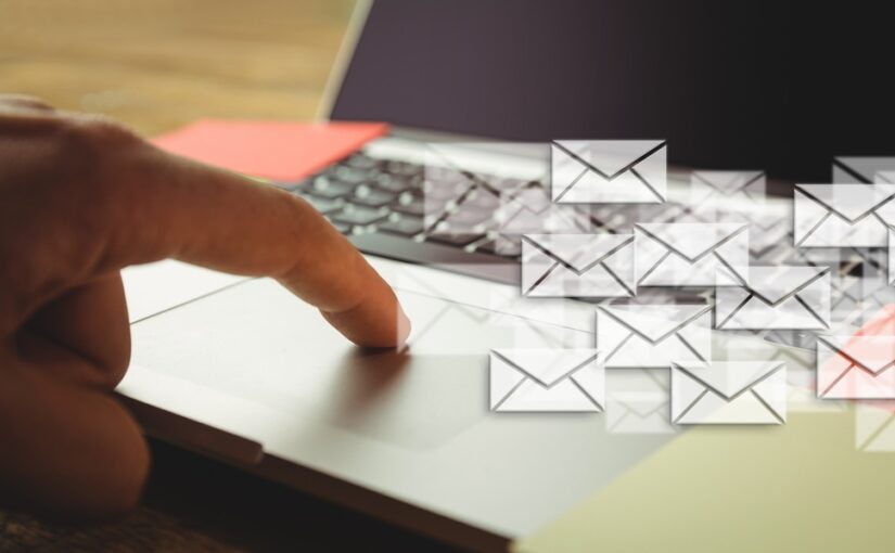 A finger on a laptop mouse board with images of envelopes overlaid.