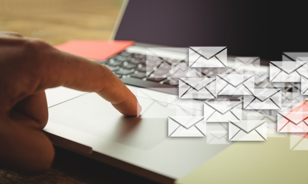 A finger on a laptop mouse board with images of envelopes overlaid.